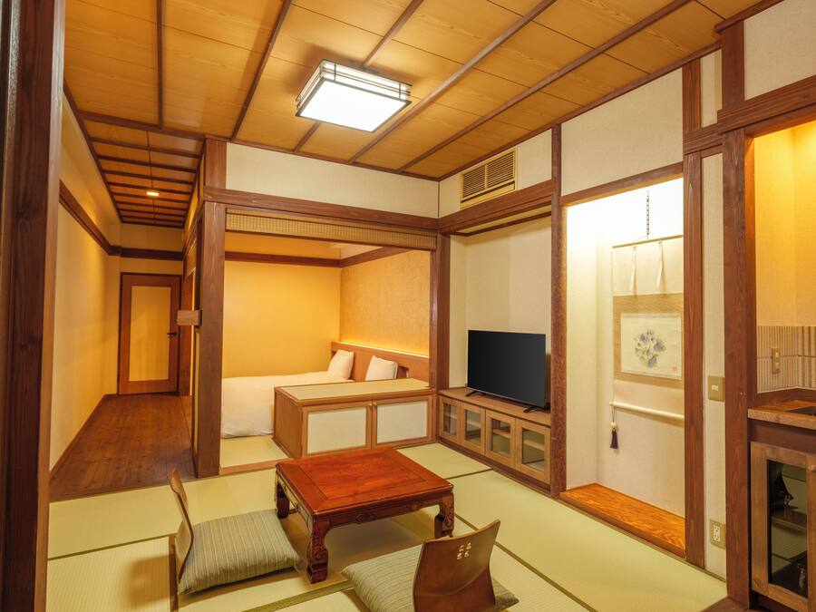 Ett traditionellt japanskt rum med tatamimattor på golvet, ett lågt träbord, en soffa och en tv.