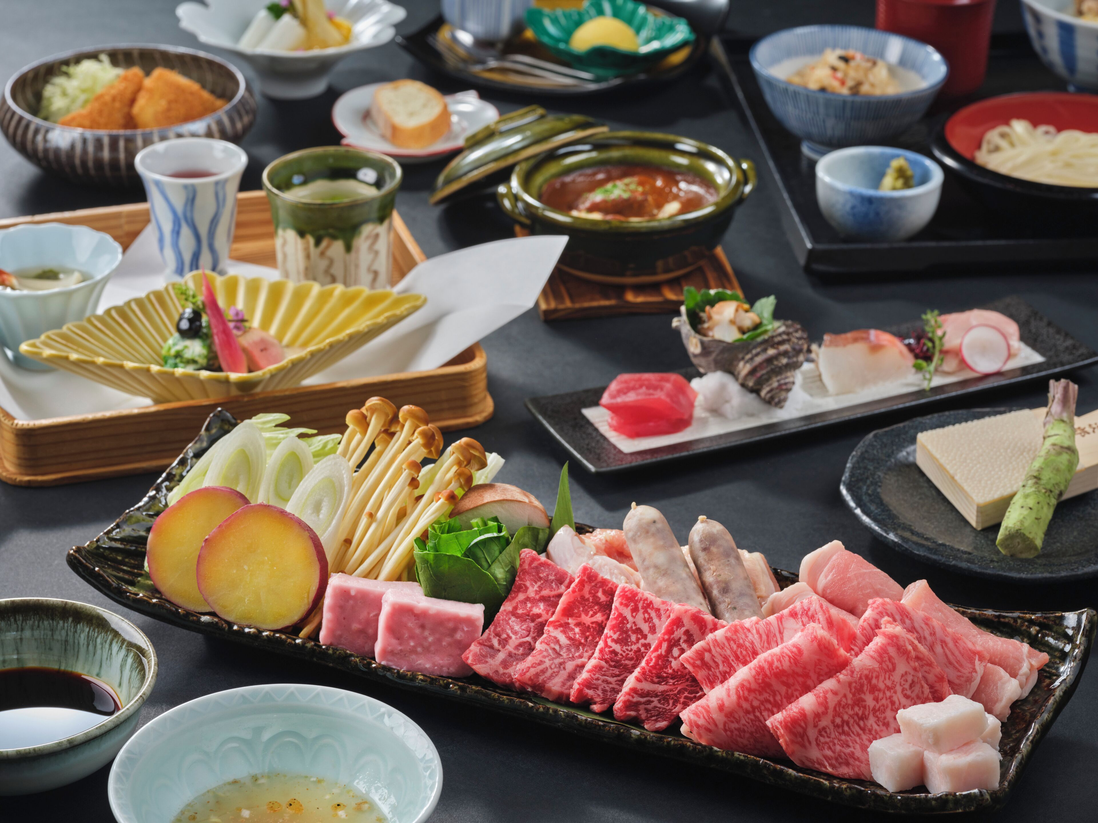 A variety of dishes including sashimi, vegetables, and pickled items on a table.