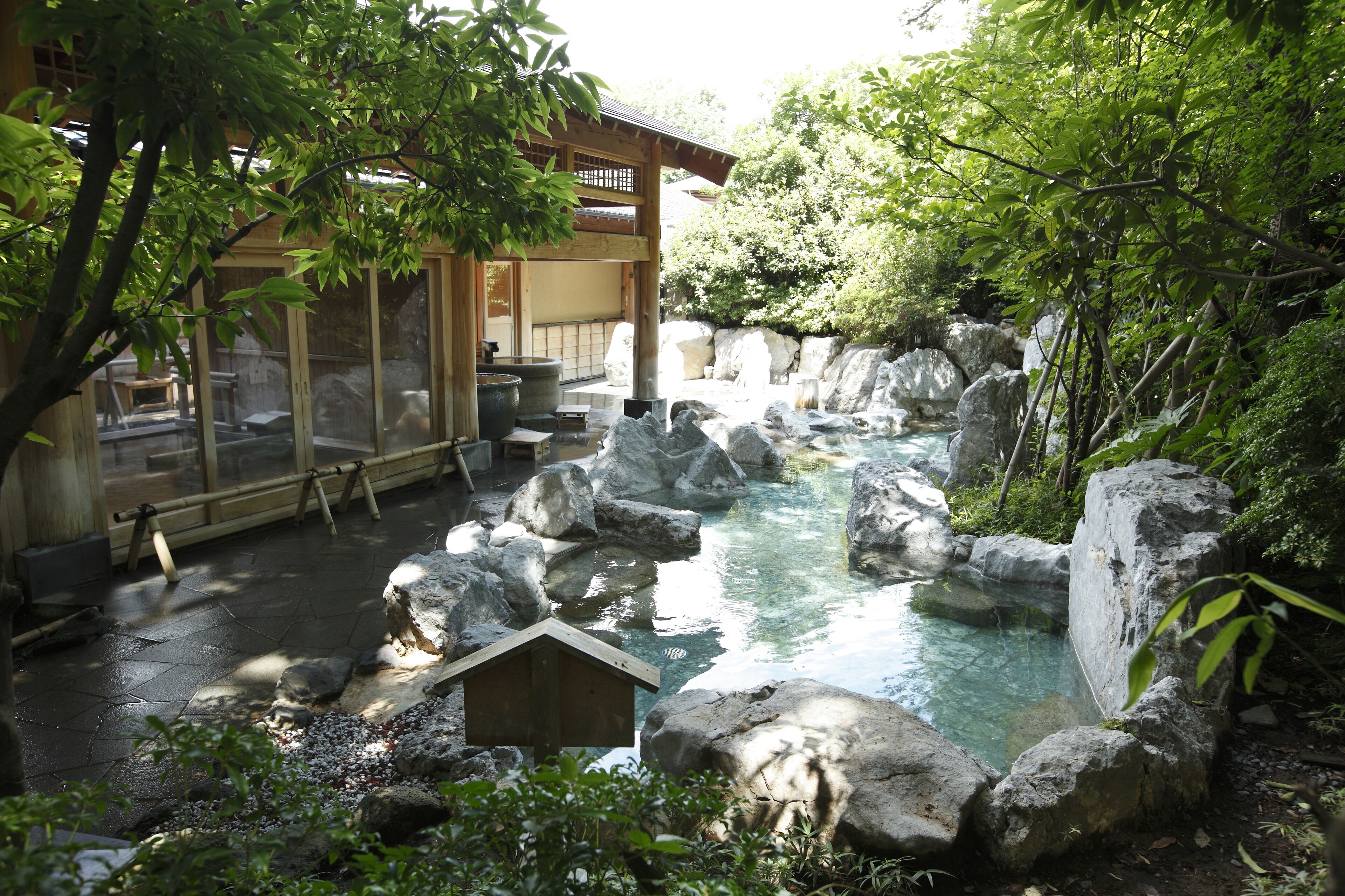 A traditional Japanese garden with a koi pond, large rocks, and a wooden structure.