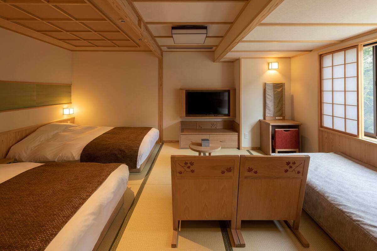 Ein Hotelzimmer mit zwei Betten, einem Fernseher, einem kleinen Tisch und einem Fenster mit Blick.