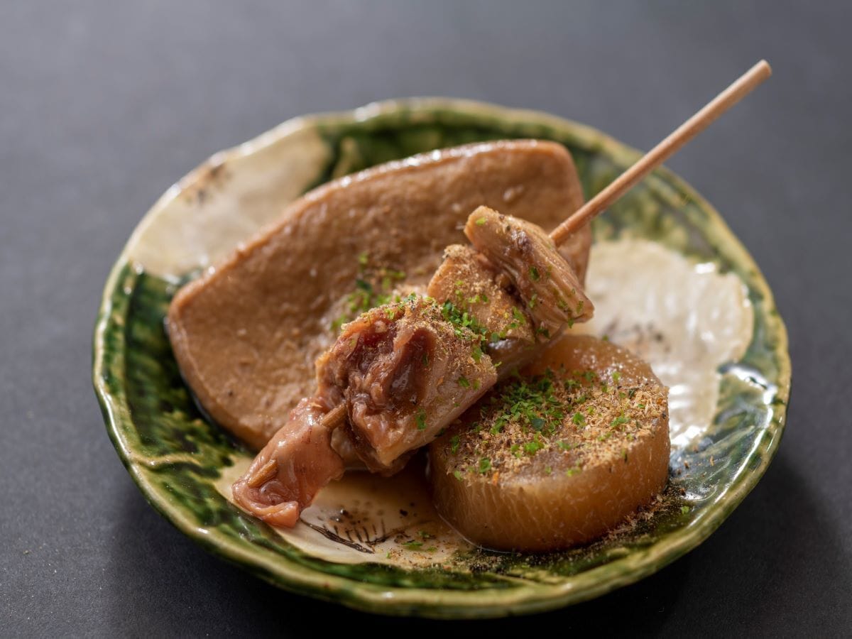 A plate with skewered meat and a round item, possibly a vegetable, garnished with herbs.