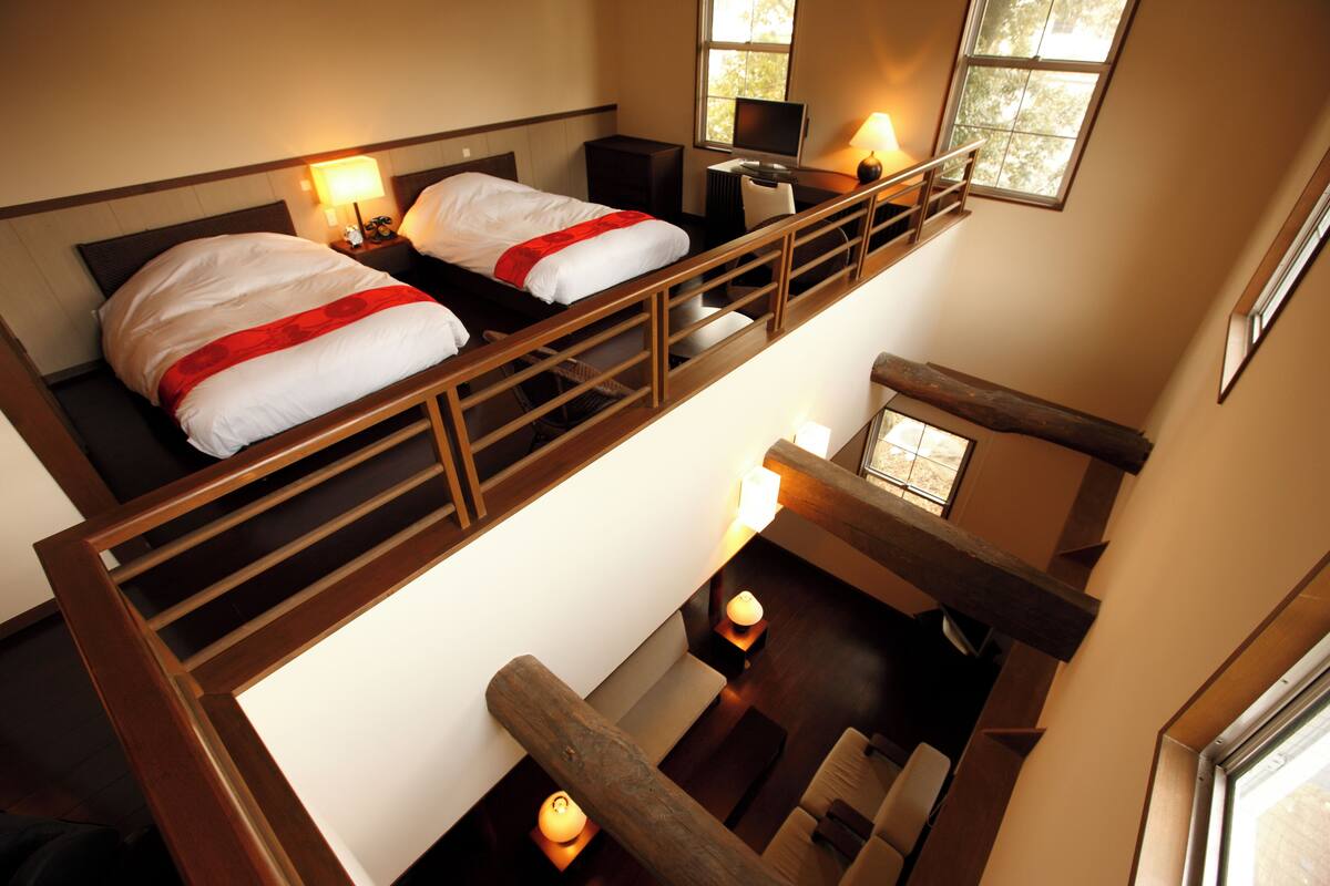 Ein Hotelzimmer mit Schlafkoje, Schreibtisch und Sitzecke mit Blick ins Freie.