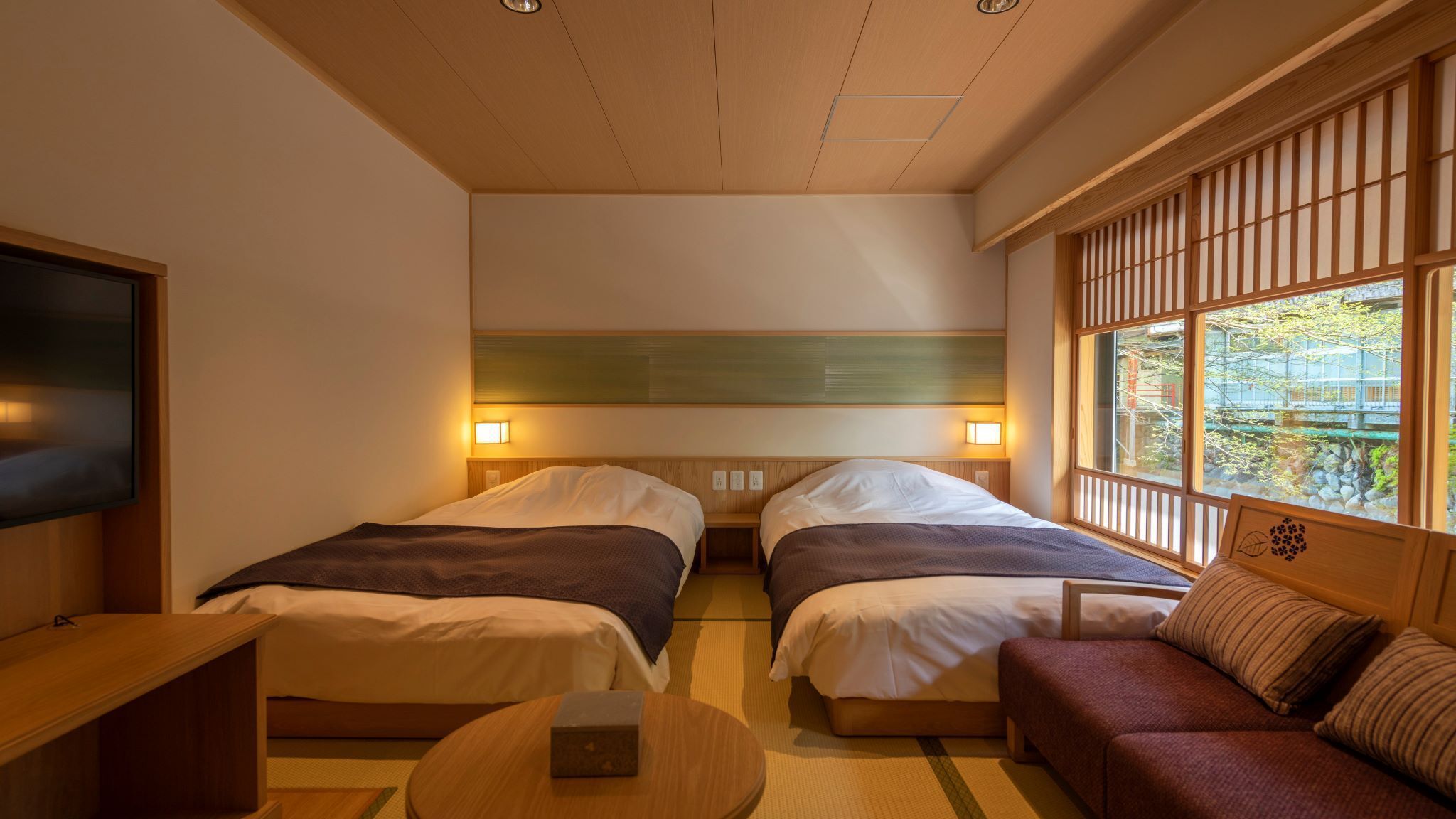 Habitación de hotel con dos camas, un sofá, un televisor y una ventana con vistas.