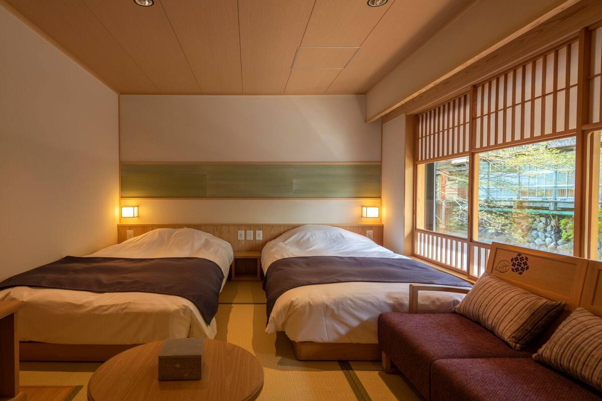 Ein Hotelzimmer mit zwei Betten, einem Schlafsofa, einem Fernseher und einem Fenster mit Blick.