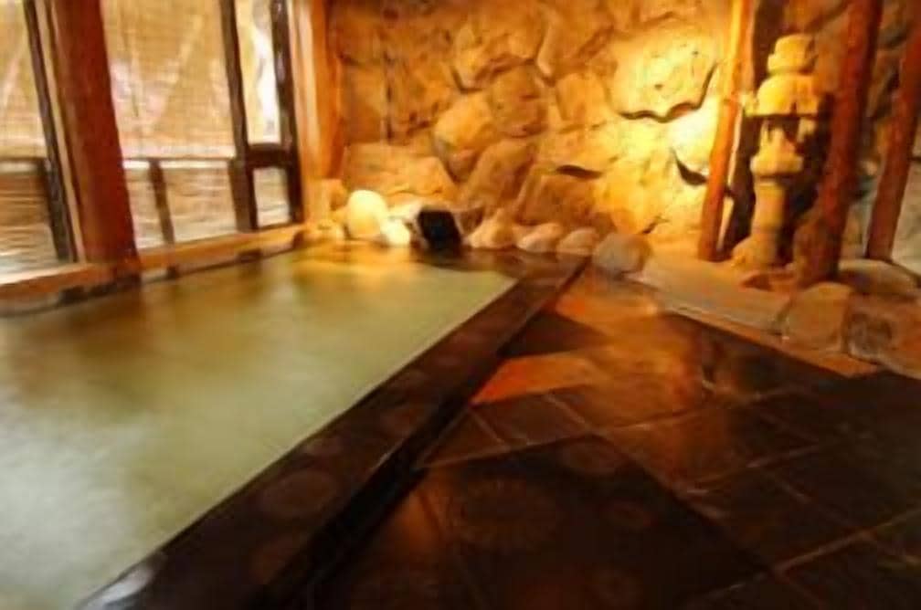 A spa area with a stone wall, a hot tub, and a wooden bench.
