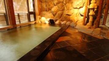 A spa area with a stone wall, a hot tub, and a wooden bench.