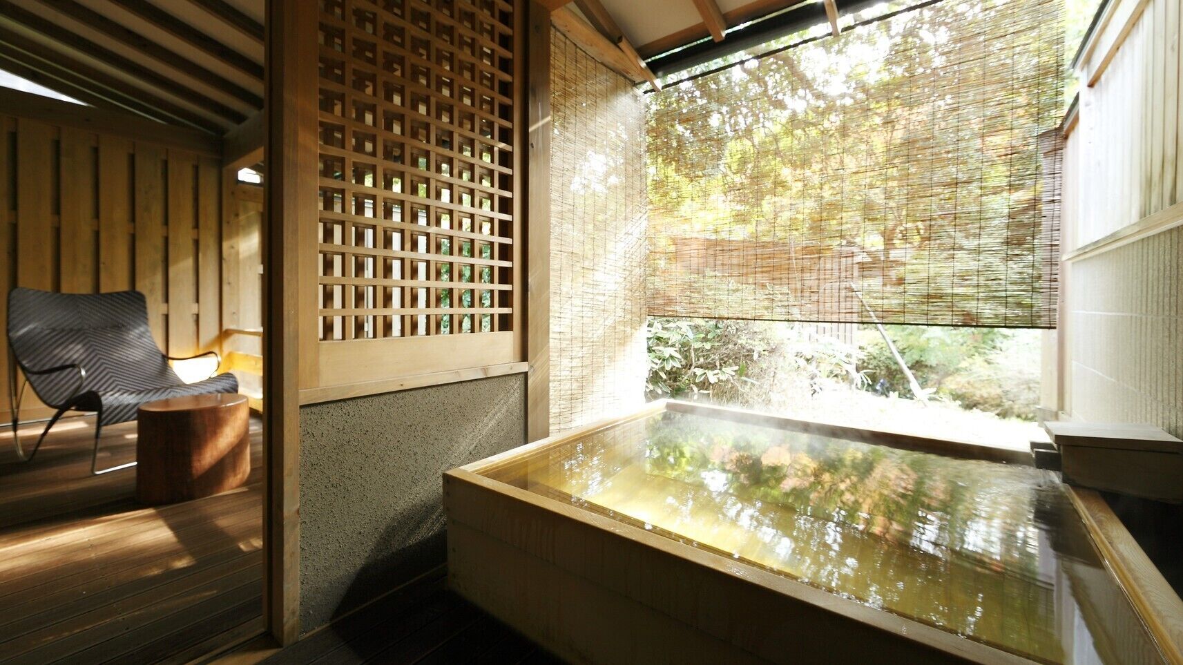 A traditional Japanese-style room with tatami flooring, a wooden sliding door, a tatami mat table, and a large window overlooking a garden.