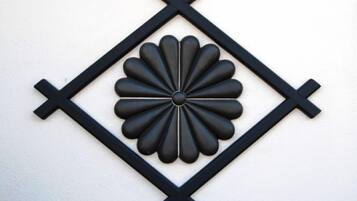 A black decorative wall piece with a central floral design surrounded by a diamond pattern.