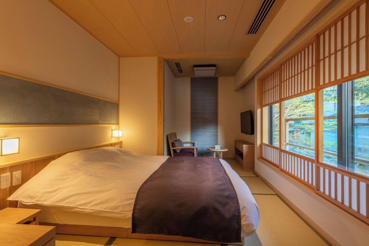 Ein Hotelzimmer mit Bett, Nachttisch, Stuhl, kleinem Tisch und Fernseher.