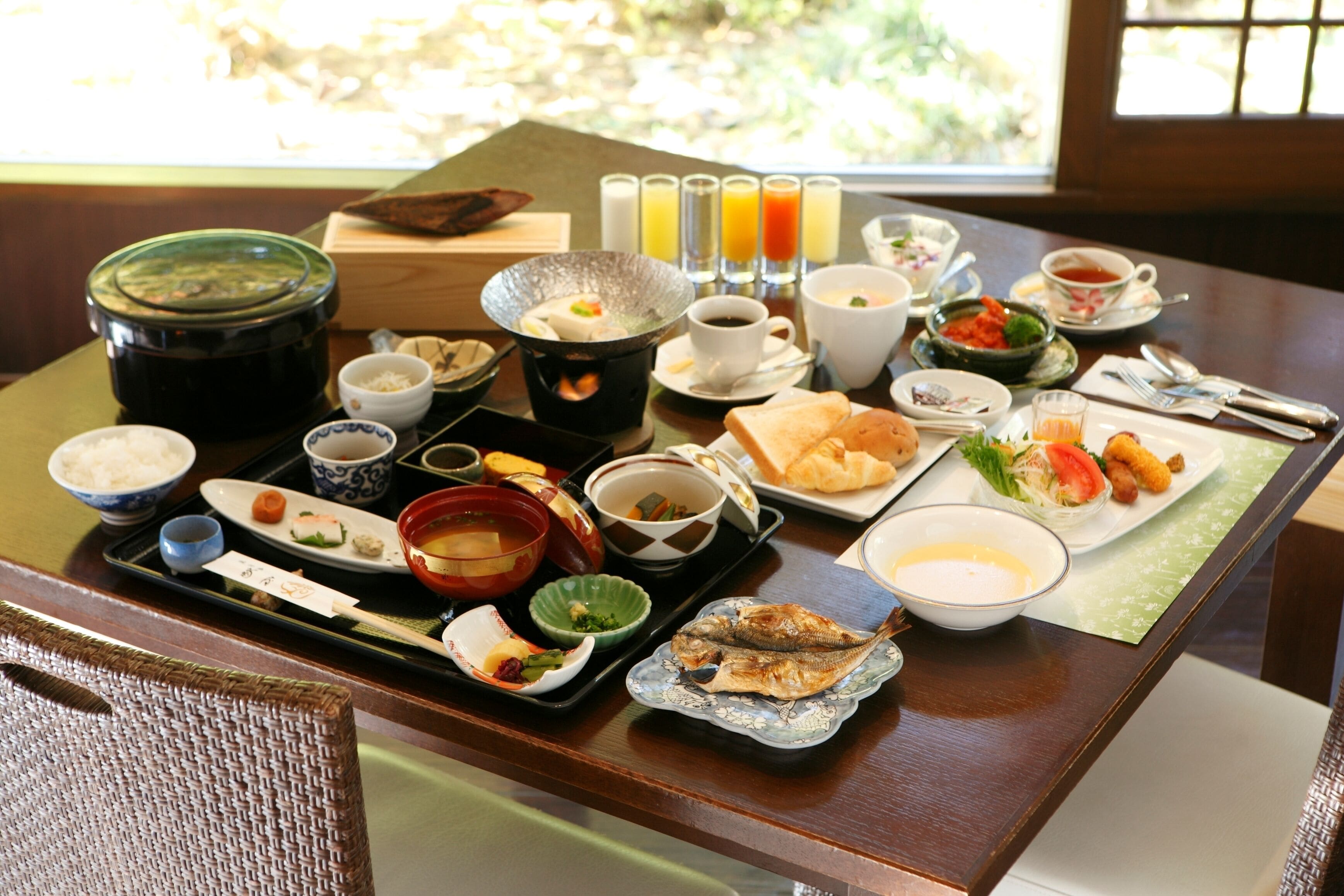 A traditional Japanese meal setup with various dishes, including sushi, soup, and grilled fish, on a wooden table.