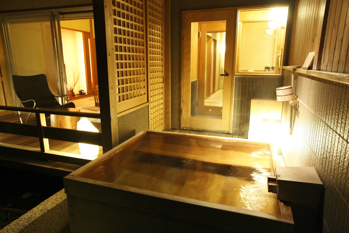 Ein traditionelles japanisches Onsen mit Holzbad, Schiebetüren und Blick ins Innere.