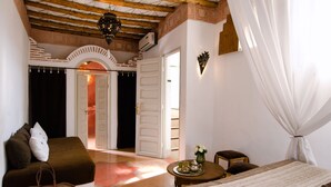 A room with a bed, a sofa, a small table with a vase, and a chair. There is a staircase leading to another room. - Riad Vert Marrakech (Marrakech)