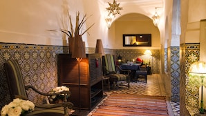 A traditional Moroccan interior with patterned tile walls, a central seating area with a table and chairs, and a decorative star-shaped light fixture. - Riad Vert Marrakech (Marrakech)