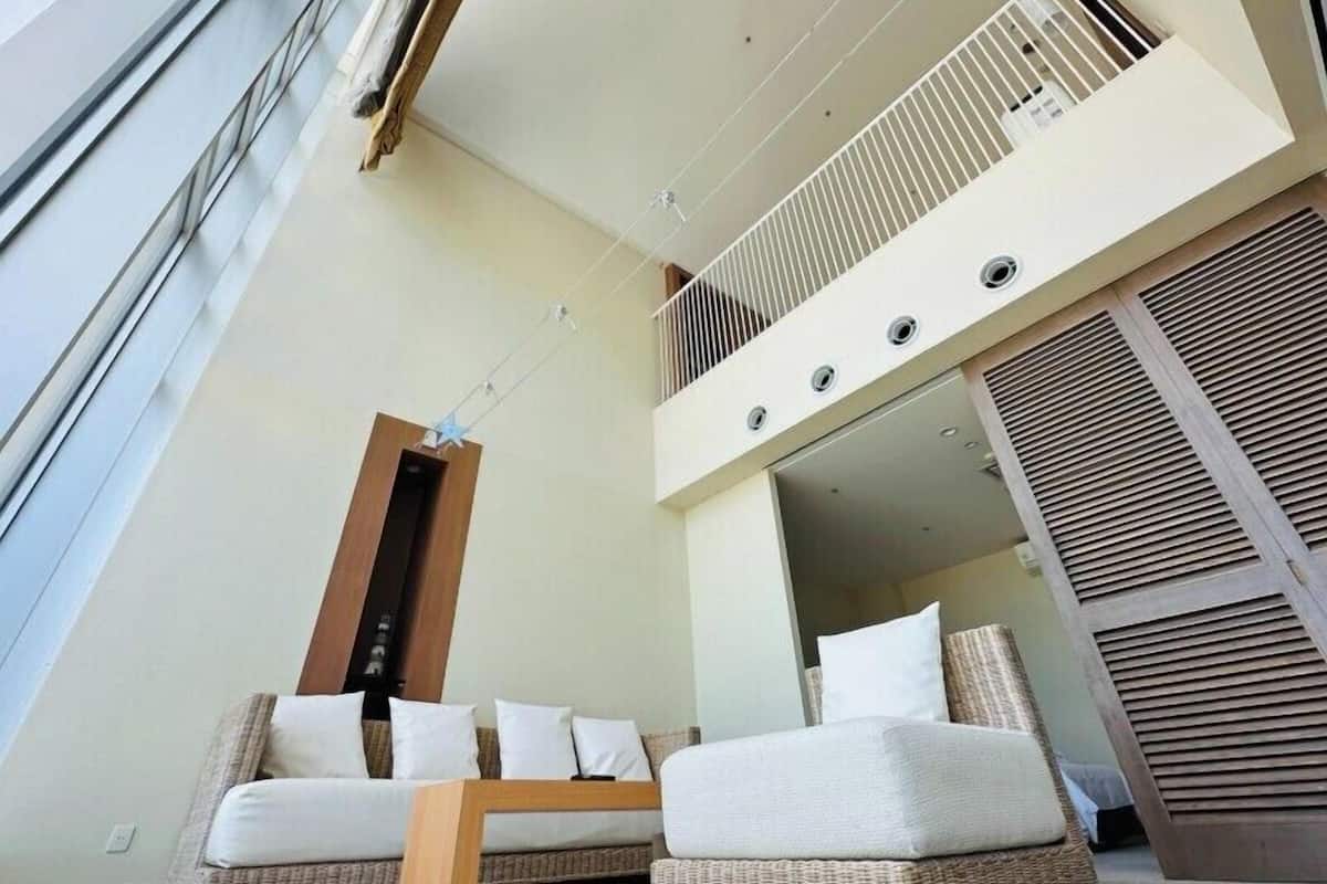 A modern interior with a balcony, wicker furniture, and a ceiling fan.