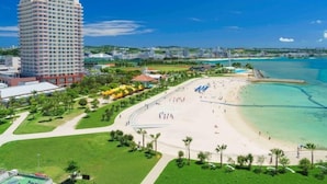 A coastal hotel with a beach view, a large building, and a clear sky.