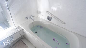 Un baño con bañera, ducha y barras de apoyo.