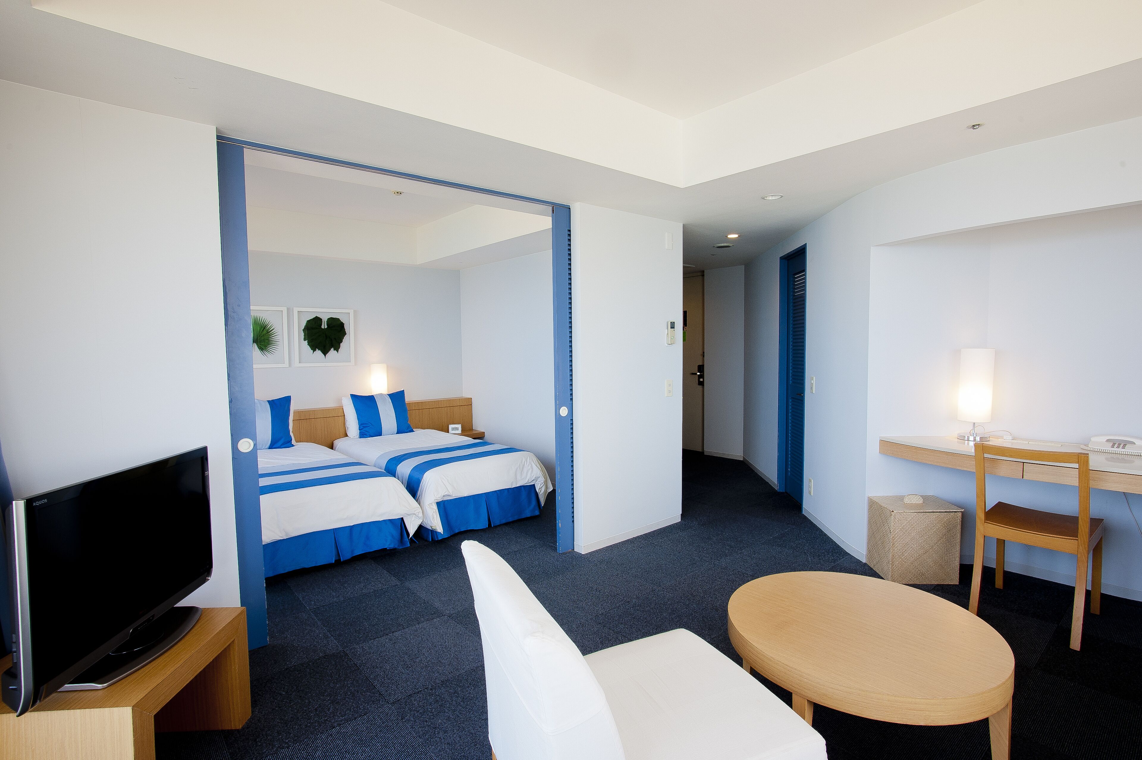 A hotel room with a bed, a TV, a desk, and a chair.