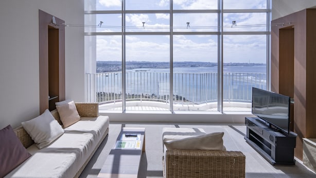 A modern living room with a large window offering a city view, a sofa, a TV, and a coffee table.