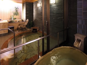 A hot tub area with a stone floor, wooden seating, and a glass partition. - Dormy Inn Sapporo Annex Hot Spring (Sapporo)