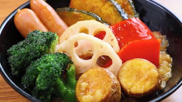 Un tazón de comida con varias verduras y una rodaja de berenjena.