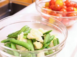 A bowl of mixed vegetables including green beans, cauliflower, and peas.