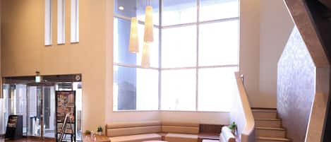 A modern lobby with a large window, a staircase, and a seating area.