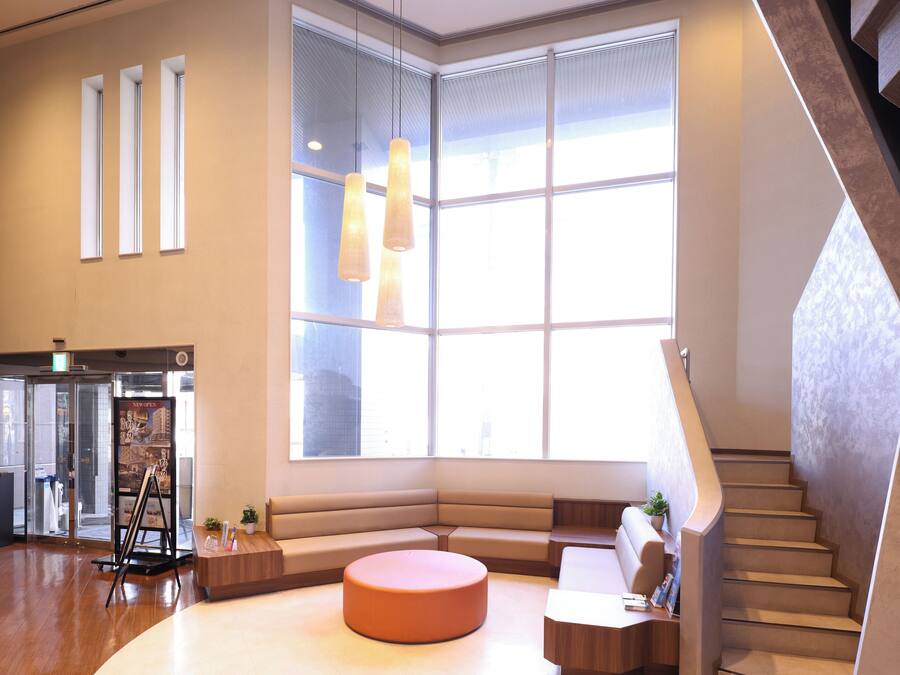 Eine moderne Lobby mit großem Fenster, einer Treppe und einer Sitzecke.
