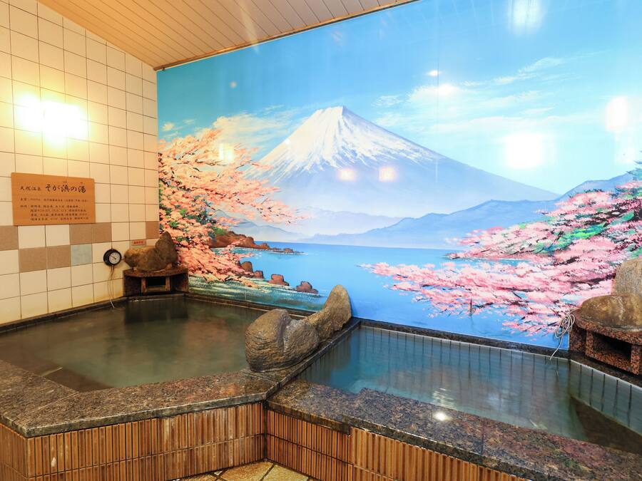 A hot spring bath with a mural of Mount Fuji and cherry blossoms.