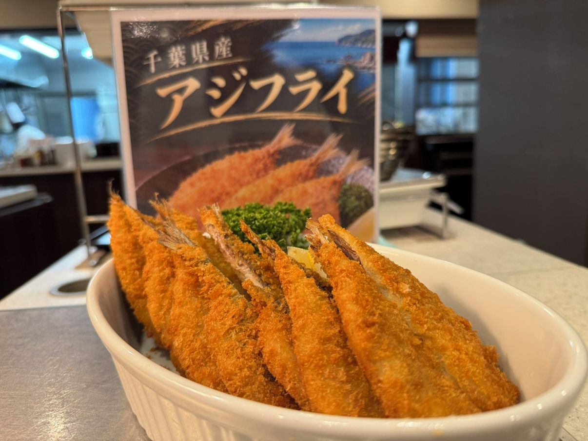 A bowl of breaded and fried food, possibly a type of fish, with a sign in the background.