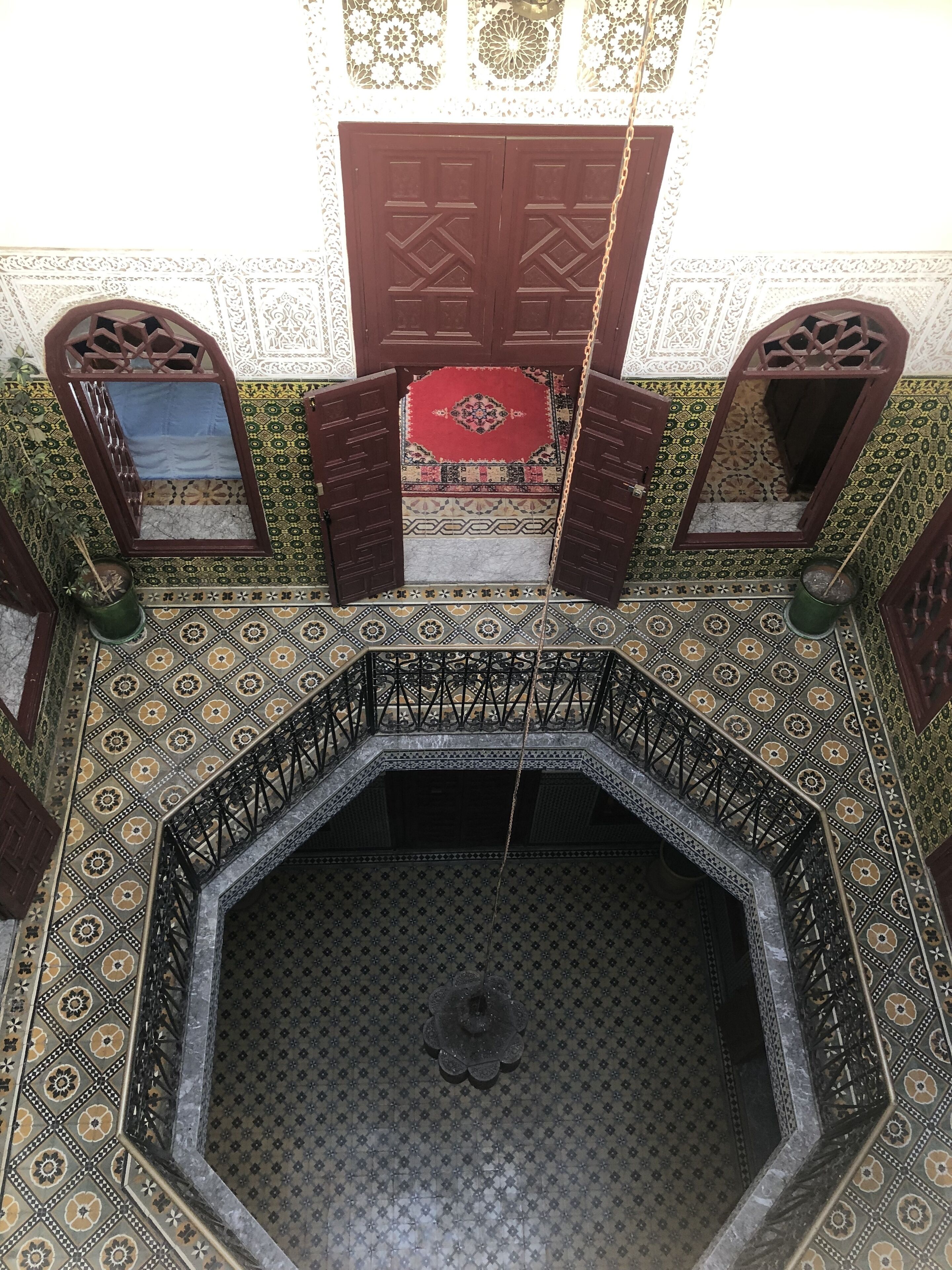 A view of a room with a patterned floor, a central octagonal fountain, and a door with a decorative frame.