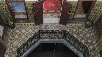A view of a room with a patterned floor, a central octagonal fountain, and a door with a decorative frame.