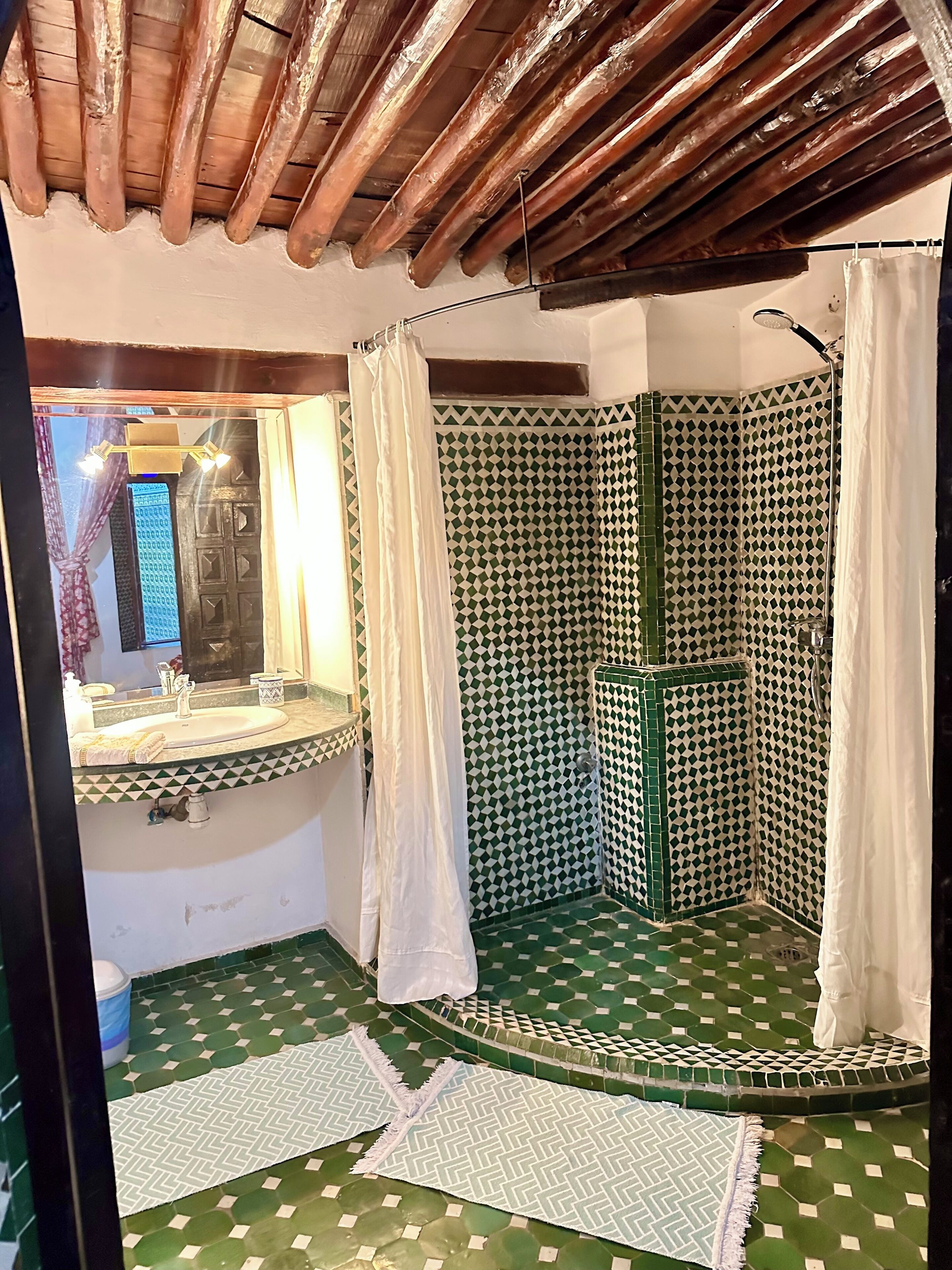 Ein Badezimmer mit Dusche, Waschbecken und Spiegel.
