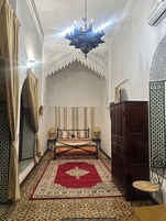 A room with a bed, a chandelier, a cabinet, and patterned walls.