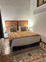 Una cama con colcha estampada, un cabecero decorativo y una alfombra con diseño en el suelo.