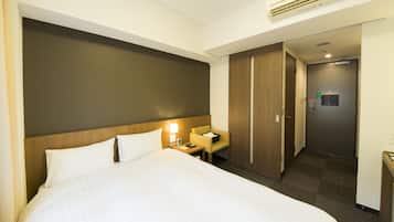 A hotel room with a large bed, a nightstand, a desk, and a wardrobe.