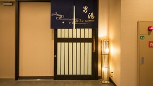 Entrada d'hotel amb una porta tradicional japonesa, un rètol que diu "Gentlemen" i una làmpada moderna al costat de la porta.