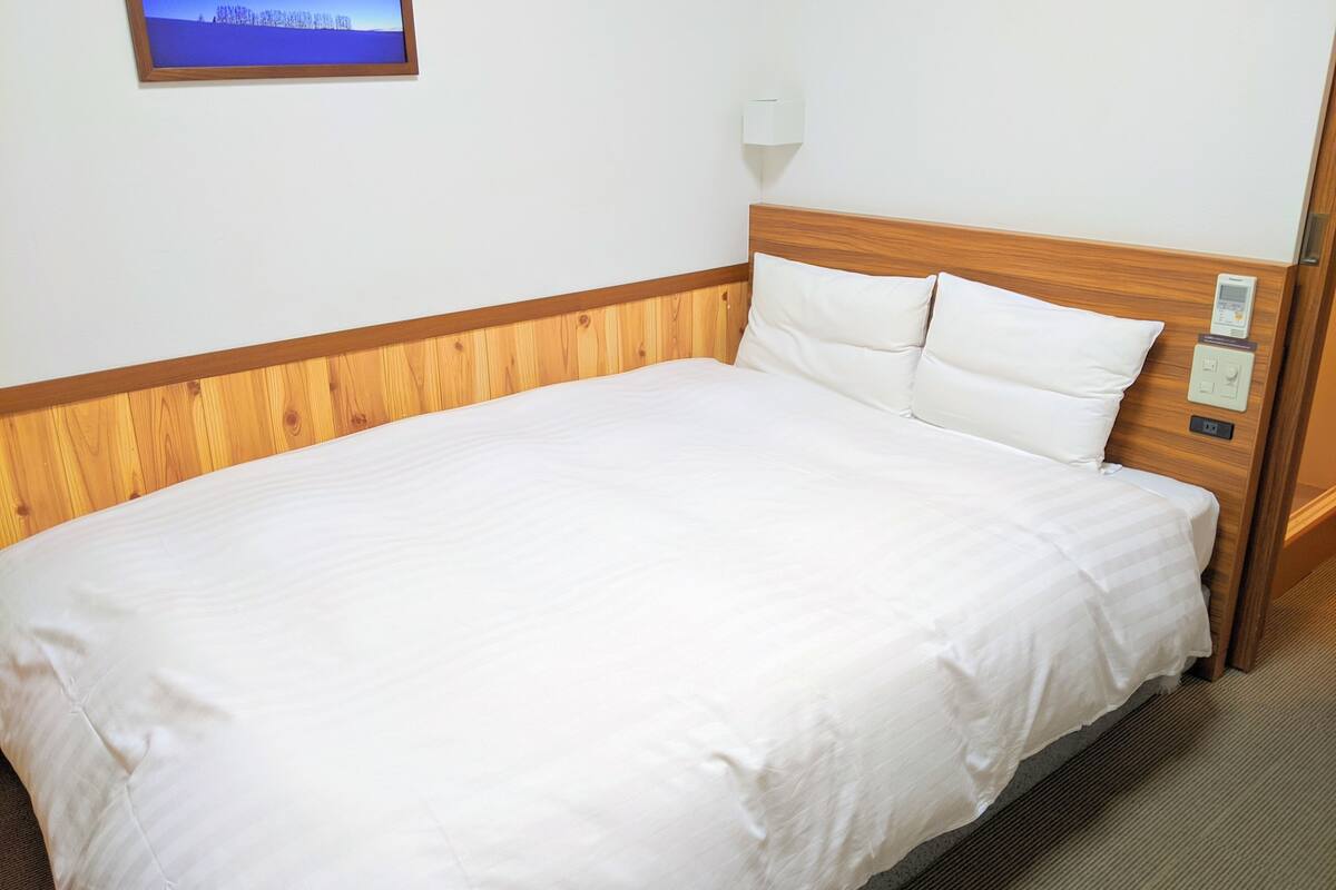 A neatly made bed with a wooden headboard and white bedding in a hotel room.