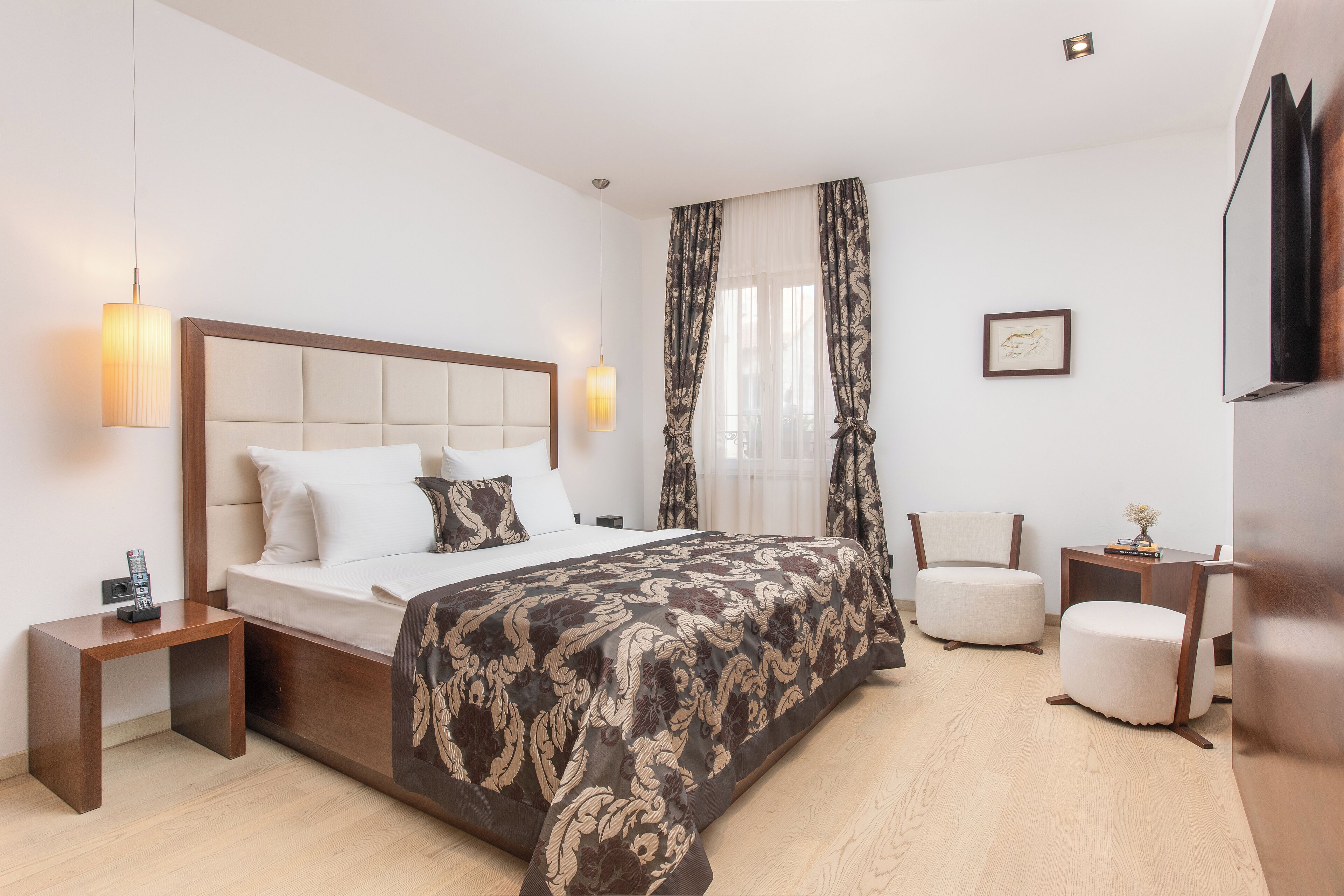 A modern hotel room with a large bed, bedside tables, a desk, and a chair.
