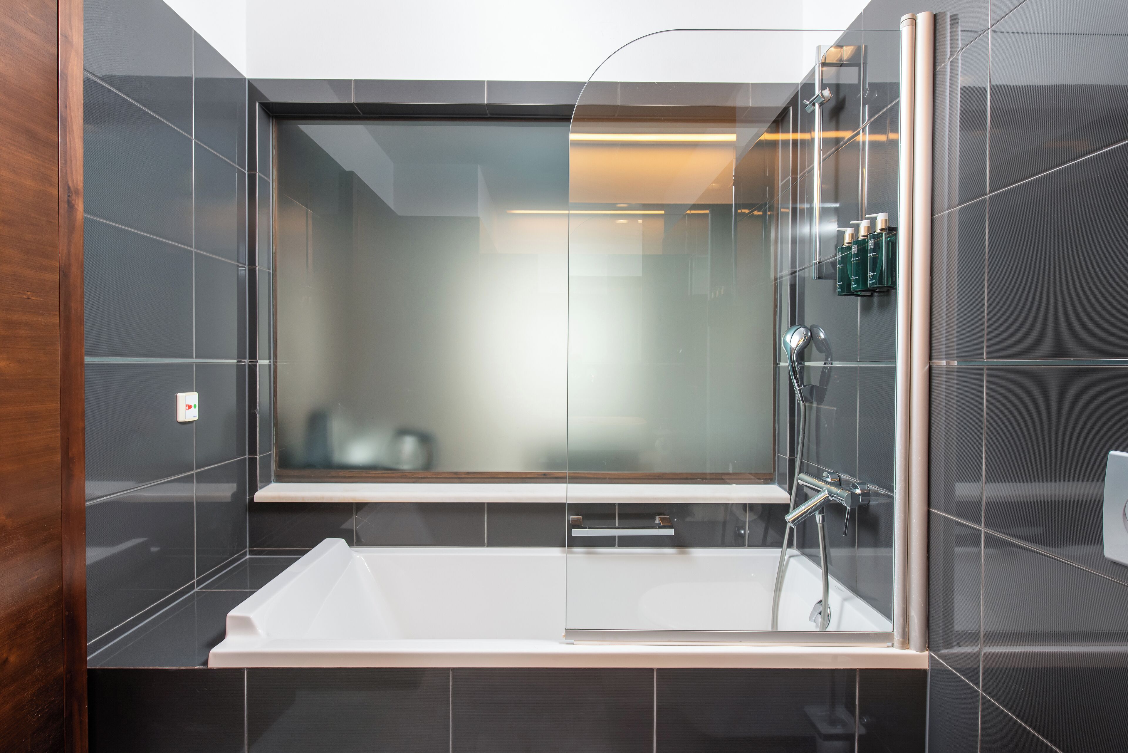 A modern bathroom with a glass-enclosed shower, a white bathtub, and a mirror above the tub.