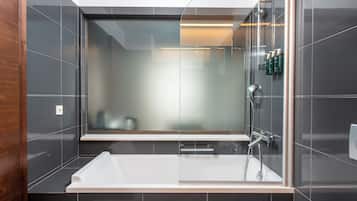 A modern bathroom with a glass-enclosed shower, a white bathtub, and a mirror above the tub.