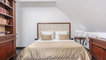 A neatly arranged bedroom with a large bed, a wooden nightstand, a bedside table, and a bookshelf.
