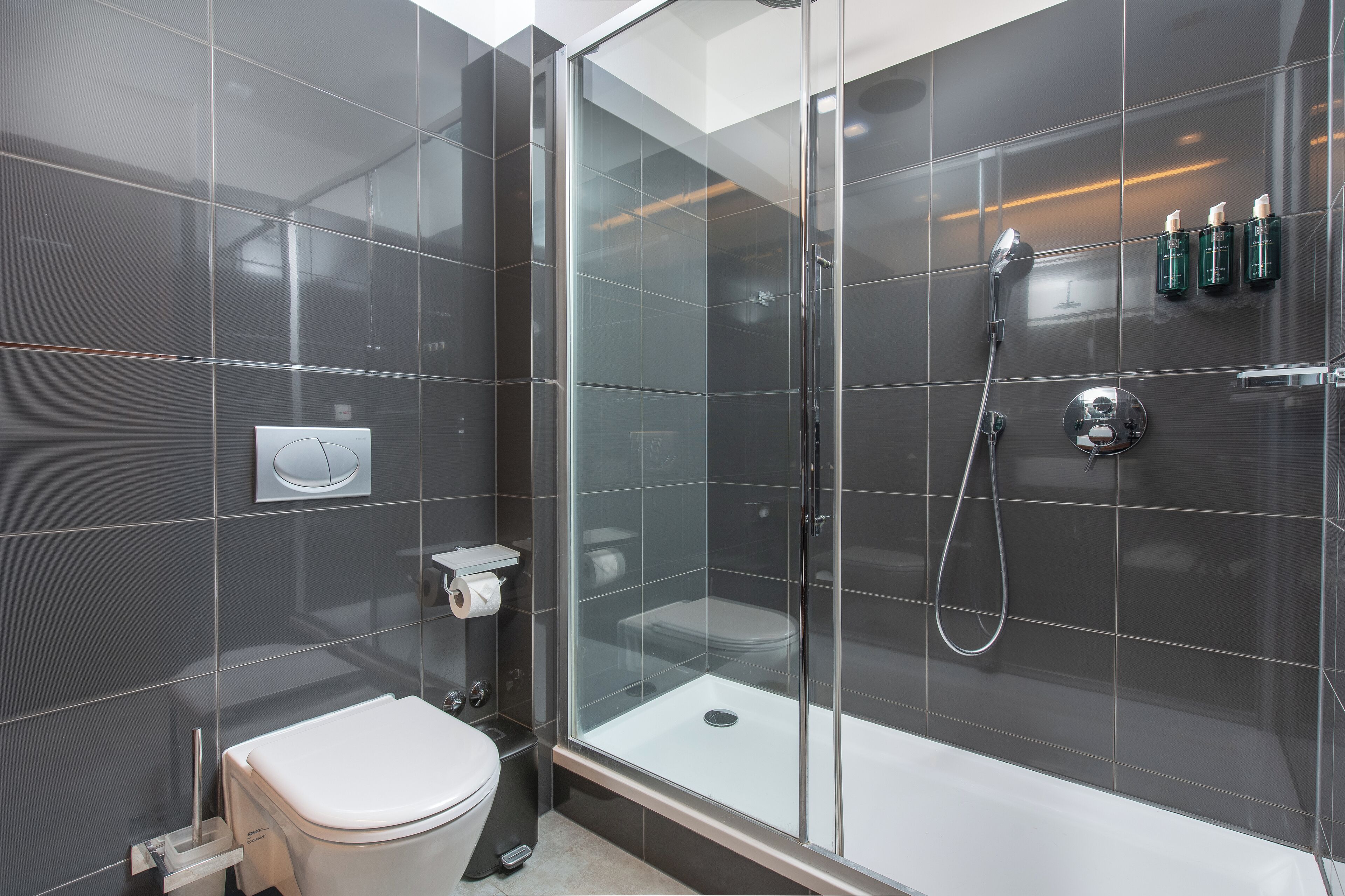 A modern bathroom with a glass-enclosed shower, a toilet, and a sink.