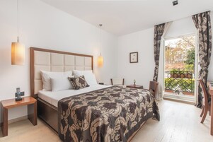 Ein modernes Hotelzimmer mit einem großen Bett, Nachttischen, einem Schreibtisch und einem Balkon mit Blick.