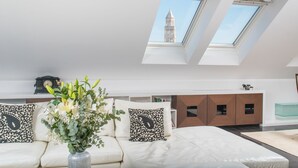 A modern living room with a white sofa, a decorative vase, and a view of a tower through skylights. - Hotel Marmont Heritage (Split)