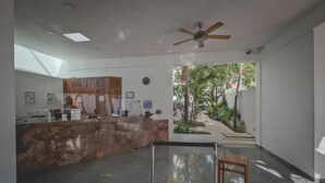 A reception area with a marble counter, ceiling fan, and natural light from a skylight. - Hotel Sotavento & Yacht Club (Cancun)
