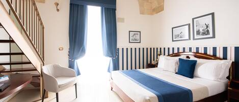 A hotel room with a bed, a desk, a chair, and a staircase.
