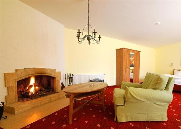 Una sala de estar con chimenea, una mesa de madera, un sofá verde y un candelabro.