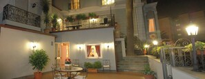 A courtyard with a dining area, a staircase, and a balcony with plants. - Villa Margherita (Naples)