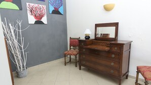 A room with a wooden dresser, a chair, a lamp, and wall art. - Villa Margherita (Naples)