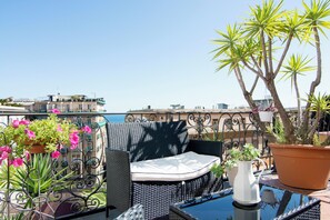 A balcony with wicker furniture, potted plants, and a view of the sea. - Villa Margherita (Naples)